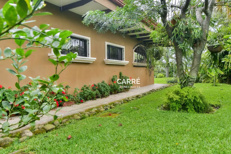 Casa de un nivel rodeada de jardines, en condominio.