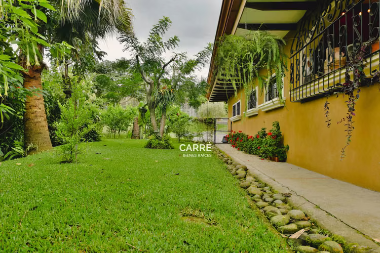 Casa de un nivel rodeada de jardines, en condominio.